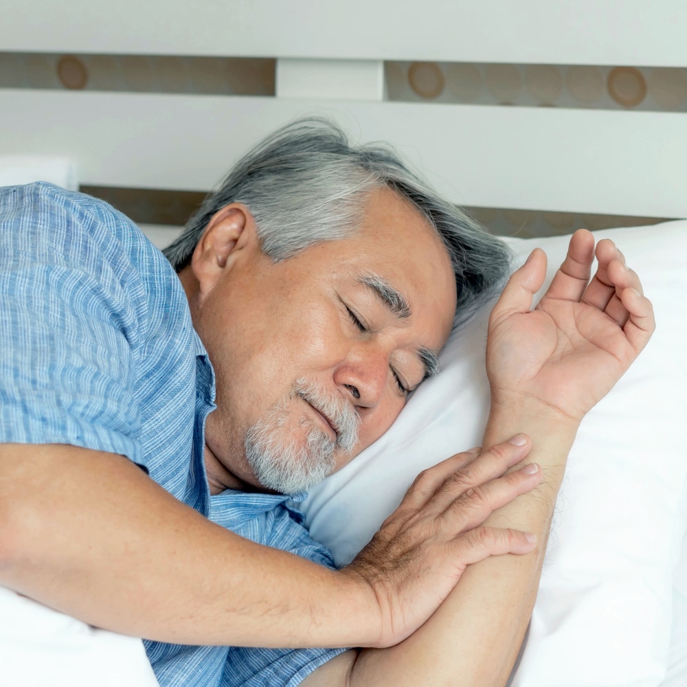 an older man sleeps in bed